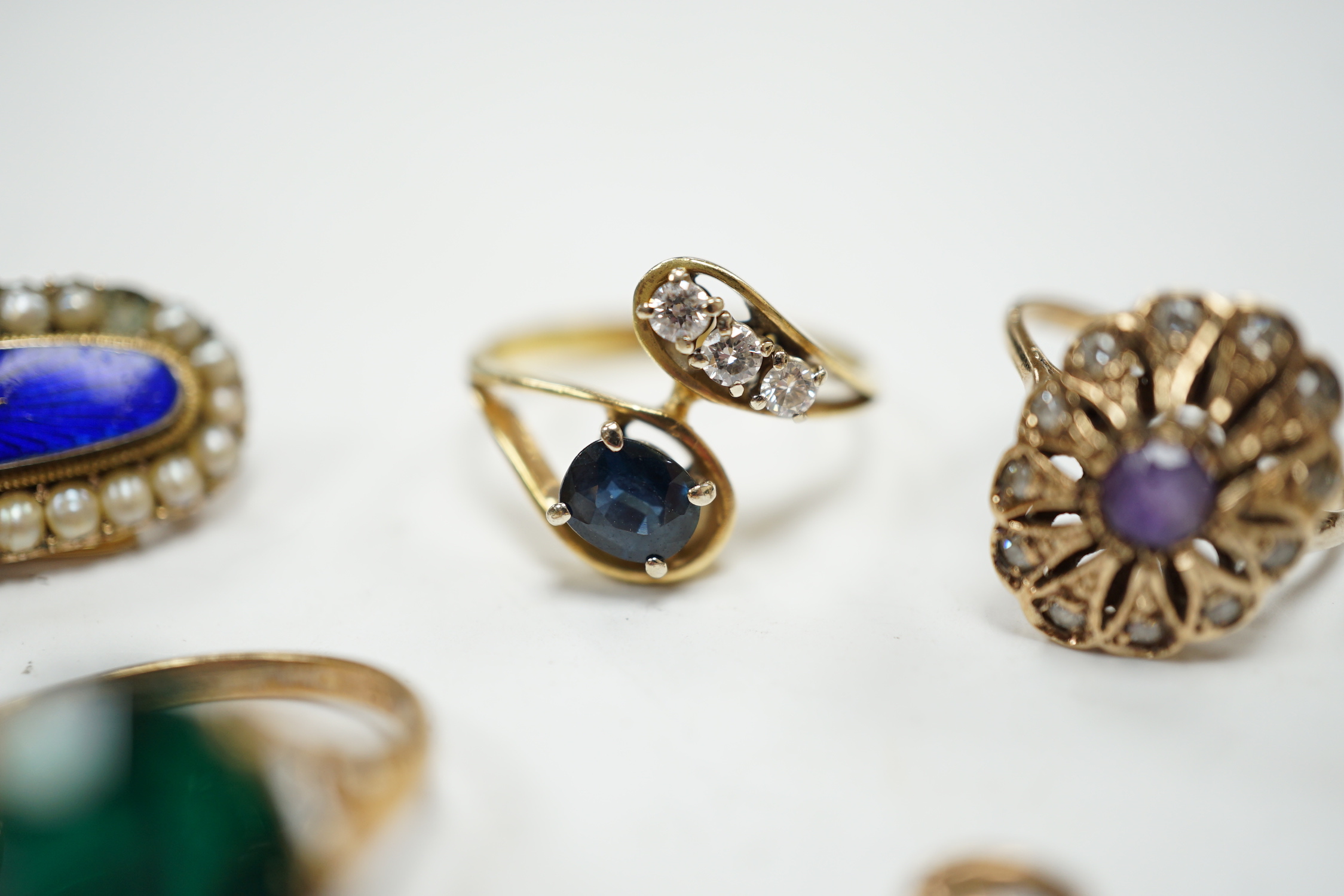 A 750 yellow metal, single stone sapphire and three stone diamond set crossover ring, size, three other yellow metal and gem set rings including a continental 875 white metal and 585 yellow metal, synthetic sapphire or s